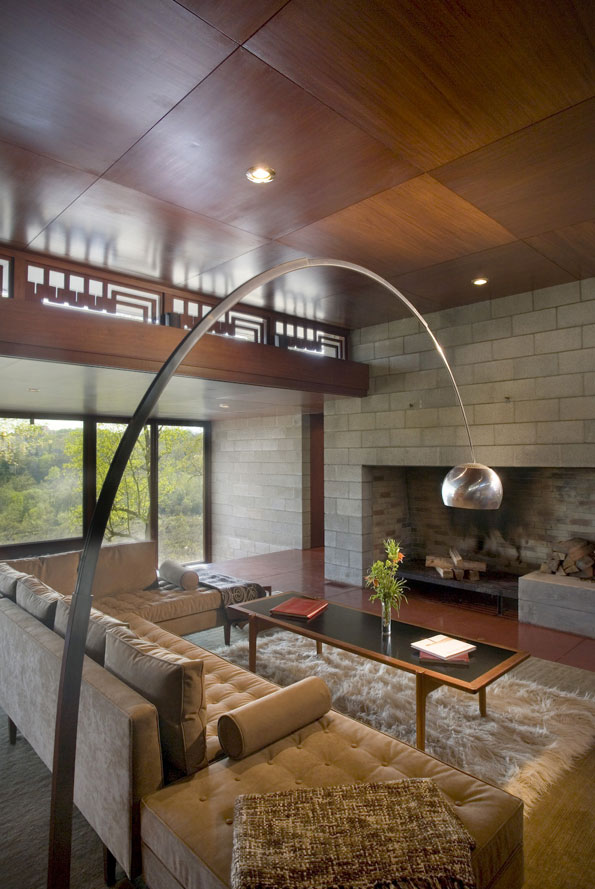 An iconic Arco floor lamp soars over the central living space toward a stone fireplace. Wright often described fireplaces as “the heart and soul of a house.”