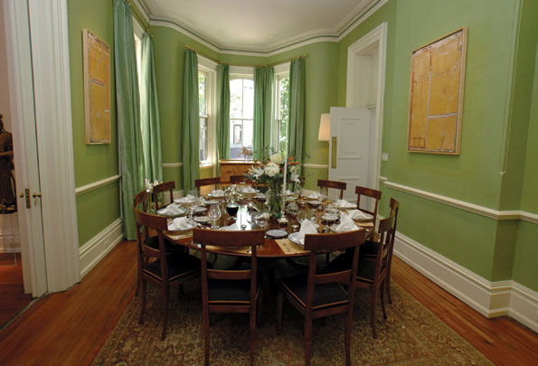 In the center of the dining room a round mahogany table can be extended with peripheral leaves to seat sixteen. 