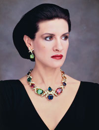 Paloma Picasso wears her bold fifth anniversary necklace (aquamarine, tanzanite, tourmaline, peridot, amethyst and topaz). The matching green tourmaline earrings also feature her signature diamond X’s.