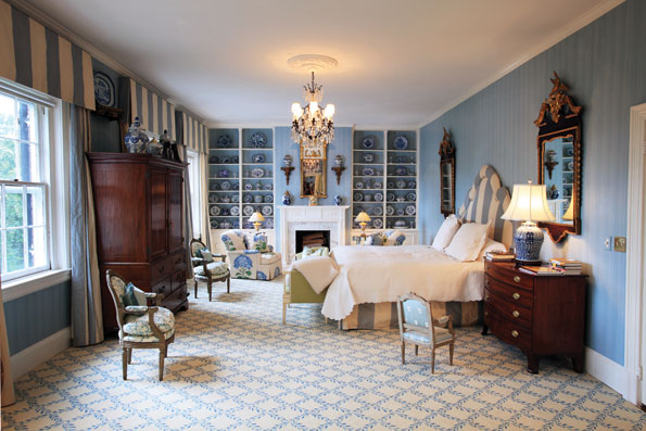 Bonnie McElveen-Hunter’s bedroom focuses on a fireplace flanked by shelves filled with her collection of blue-and-white porcelain. 