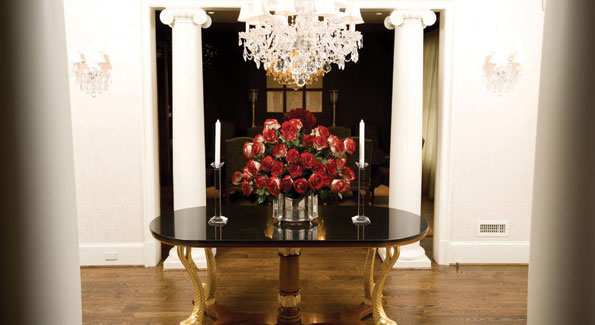 Despite ornate elements, the columns, crystal, and gilt carved table legs are perfectly proportioned to the foyer, which greets guests by hinting at the elegance to be found within