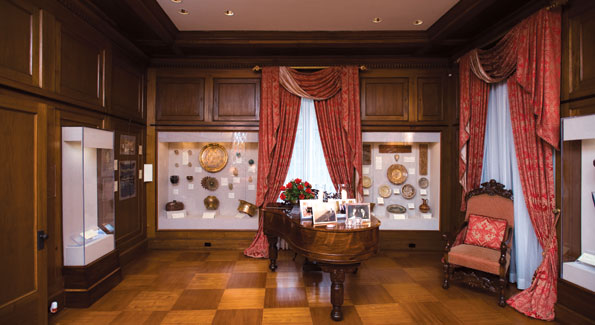 An antiquities collection surrounds a grand piano topped by family portraits. Photos by Joseph Allen.