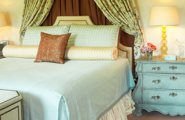 Cascading embroidered bed curtains are tempered by a tailored counterplane while a persimmon-colored carpet sets off maize-toned upholsteries. Photo by Marcos Galvany. 