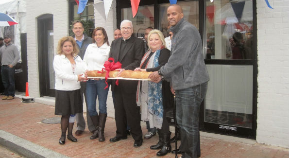 Why cut a ribbon when you can break bread? Guests gathered in front of the store to celebrate the official opening with the breaking of the bread and confetti. (Photo by Erica Moody)